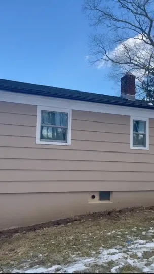 Beige horizontal lap siding on house exterior wall with brick chimney in winter