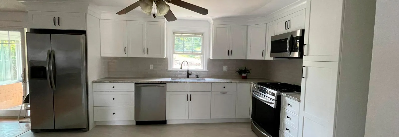 Completed white kitchen with stainless appliances and tile backsplash in Connecticut