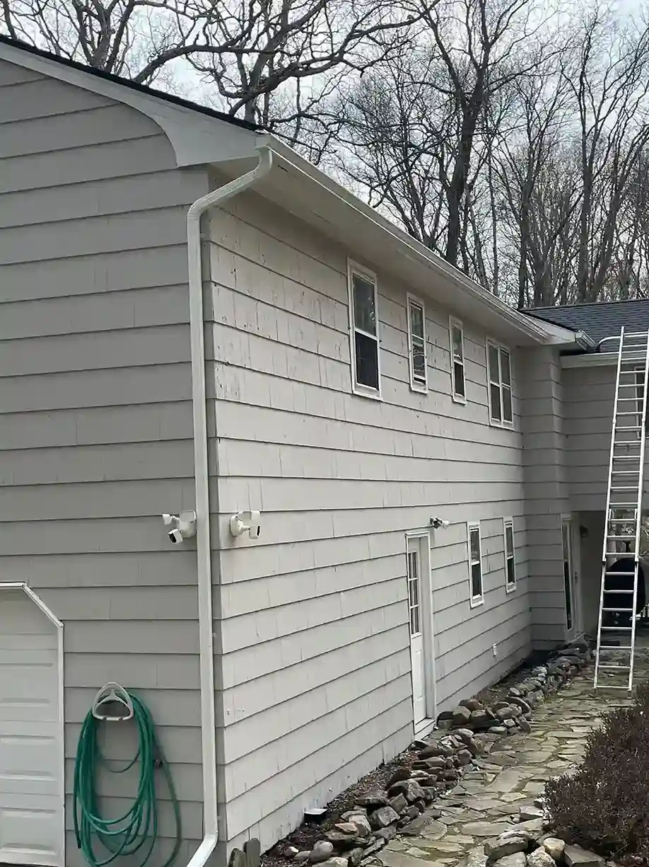 Gray lap siding house exterior with white seamless gutter and downspout