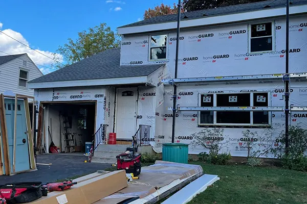 House with HomeGuard house wrap during siding replacement, scaffolding and tools