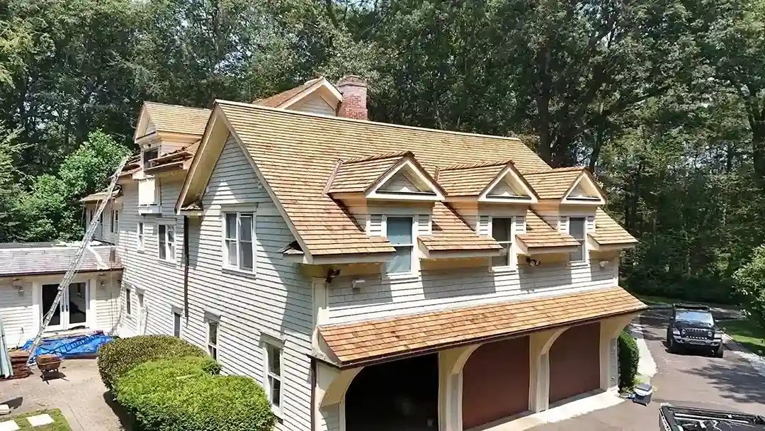 Aerial view of house with new wood shake roof and dormers over garage in Connecticut
