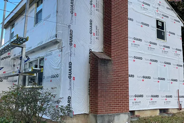 House wrapped in HomeGuard house wrap during siding renovation with brick chimney