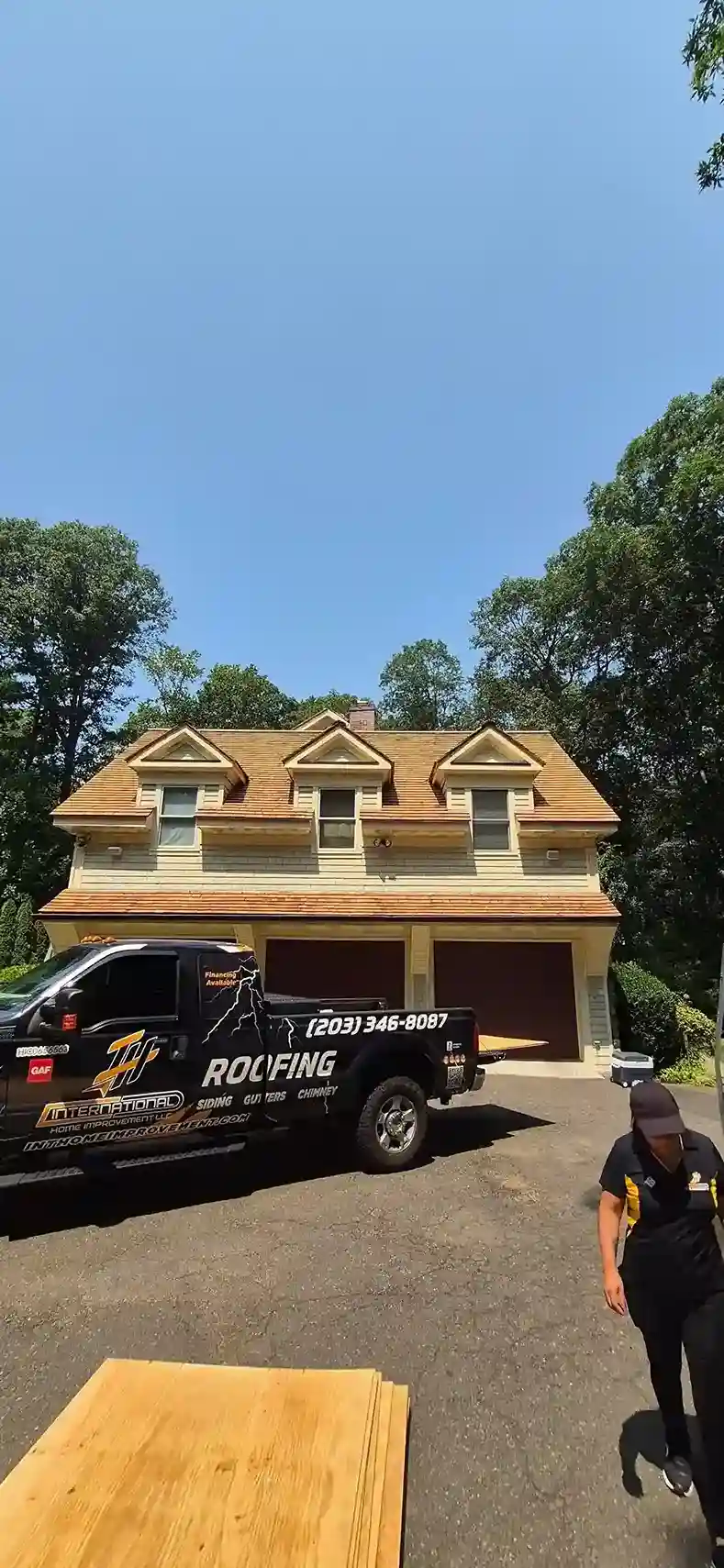 International Roofing branded truck parked in front of house with new cedar shake roof in Connecticut