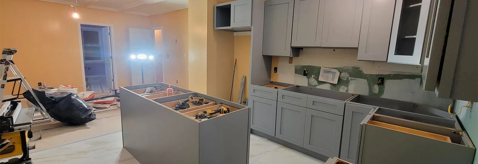 Kitchen under construction with gray cabinets, island and tools