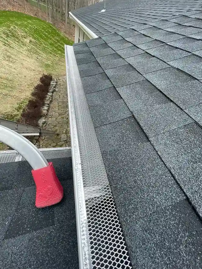 New metal mesh gutter guard installed along asphalt shingle roof edge in Connecticut