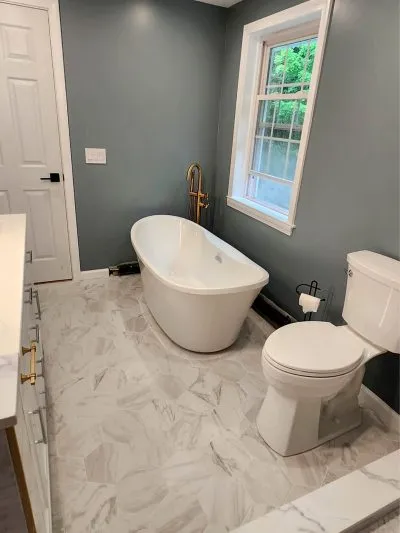 Modern bathroom with freestanding tub, gold filler and marble floor in Connecticut