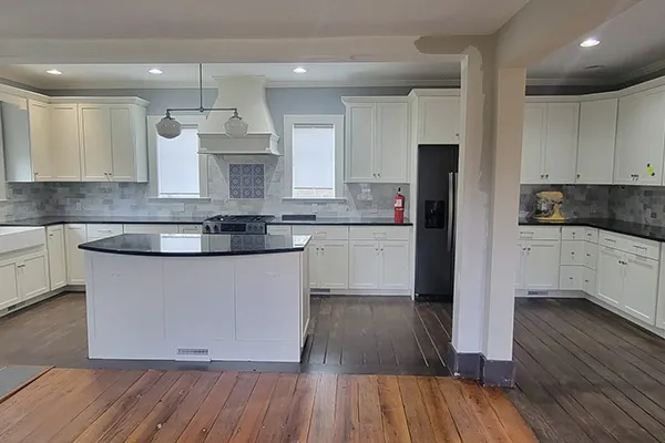 White kitchen with black granite counters and curved island after renovation